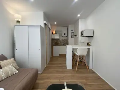 a living room with a couch and a kitchen at Mon petit studio à la mer in Gruissan