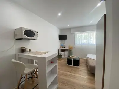 a white room with a desk and a bed at Mon petit studio à la mer in Gruissan