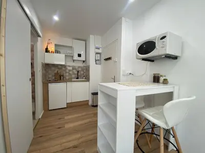 a small kitchen with a white counter and a table at Mon petit studio à la mer in Gruissan