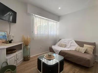 a living room with a couch and a table at Mon petit studio à la mer in Gruissan