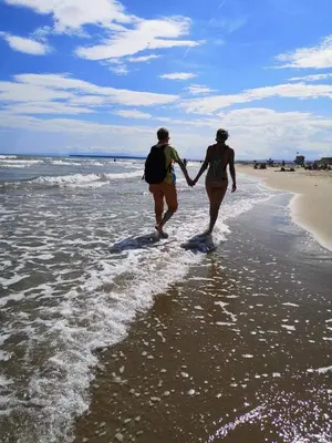 two people walking on the beach holding hands at Duplex proche mer, avec swimspa terrasse, jardin et barbecue in Lapalme