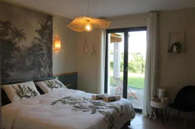 a bedroom with a large bed and a large window at La Naillousaine in Nailloux