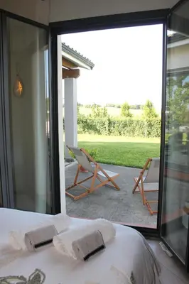 a bedroom with a bed and a view of a patio at La Naillousaine in Nailloux