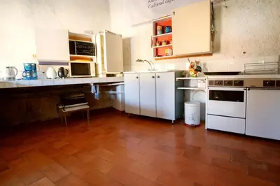 a kitchen with white appliances and a wooden floor at La Maison Bleue in Oupia