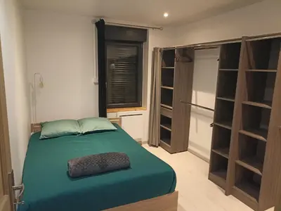 a bedroom with a green bed and a window and shelves at Location de vacances à Quarante Gîte de la cave Szymczak in Quarante
