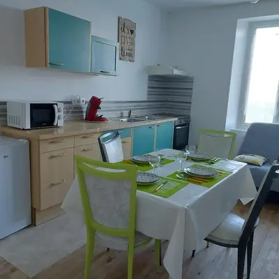a kitchen with a table with a white tablecloth and green chairs at Charmant appartement proche Carcassonne in Escueillens