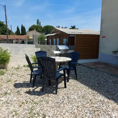 a table and chairs sitting on a gravel patio at Charmant appartement proche Carcassonne in Escueillens