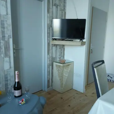a room with a table with a bottle of wine and a television at Charmant appartement proche Carcassonne in Escueillens