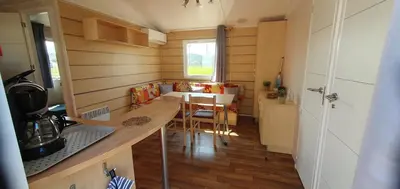 a small kitchen with a table and a dining room at MH135 camping NOVELA - location entre particuliers- Mobil home 5pl climatisé - in Port-la-Nouvelle