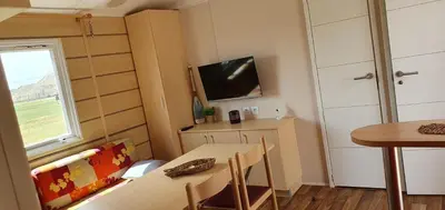 a small dining room with a table and a tv at MH135 camping NOVELA - location entre particuliers- Mobil home 5pl climatisé - in Port-la-Nouvelle
