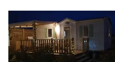 a house with lights on the front porch at night at MH135 camping NOVELA - location entre particuliers- Mobil home 5pl climatisé - in Port-la-Nouvelle