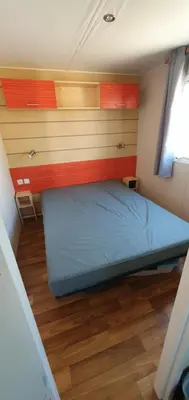 a small bedroom with a blue bed and wooden floors at MH135 camping NOVELA - location entre particuliers- Mobil home 5pl climatisé - in Port-la-Nouvelle