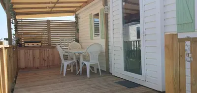 a patio with a table and chairs on a deck at MH135 camping NOVELA - location entre particuliers- Mobil home 5pl climatisé - in Port-la-Nouvelle