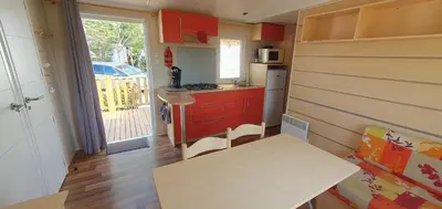 a small kitchen with a table and a counter top at MH135 camping NOVELA - location entre particuliers- Mobil home 5pl climatisé - in Port-la-Nouvelle