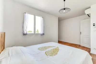 a white bedroom with a bed with a leaf painted on it at La Villa d'Isa et Seb in Narbonne