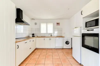 a kitchen with white cabinets and a tile floor at La Villa d'Isa et Seb in Narbonne