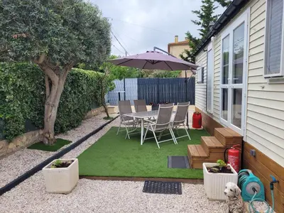 a small backyard with a table and an umbrella at Mobil home de Patricia et Franck à Sigean in Sigean