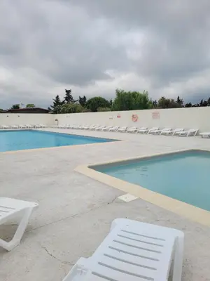 a swimming pool with white lounge chairs next to a swimming pool at Mobil home de Patricia et Franck à Sigean in Sigean