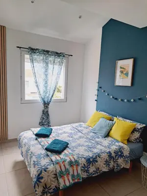 a bedroom with a bed with a blue headboard and a window at Confort et Style Maison Cosy 3 Chambres Narbonne in Narbonne