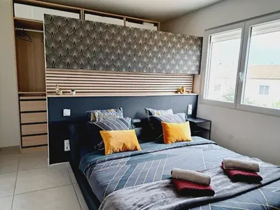 a bedroom with a large blue bed with orange pillows at Confort et Style Maison Cosy 3 Chambres Narbonne in Narbonne