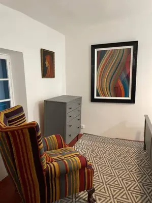 a bedroom with a bed and a chair and a dresser at Rue Basse - village house overlooking the Pyrenees in Montréal