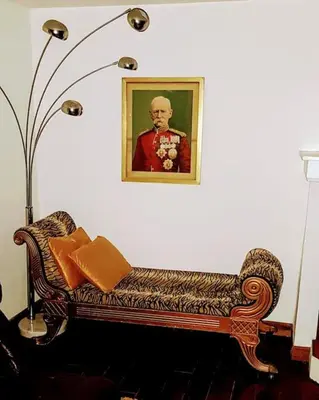 a couch in a living room with a portrait of a man at Rue Basse - village house overlooking the Pyrenees in Montréal