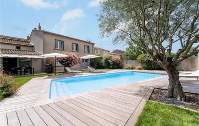 a swimming pool with a tree next to a house at Beautiful Home In Villegly With Kitchen in Villegly