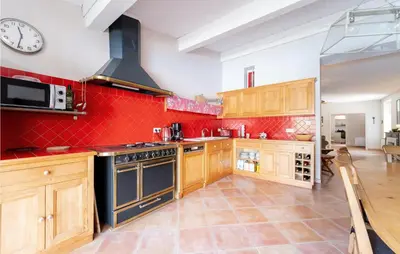 a large kitchen with wooden cabinets and a clock on the wall at Beautiful Home In Villegly With Kitchen in Villegly