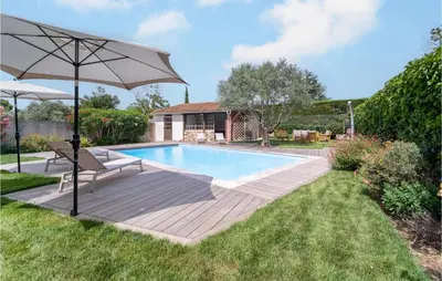 a swimming pool with an umbrella next to a yard at Beautiful Home In Villegly With Kitchen in Villegly