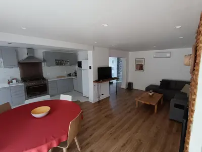 a kitchen and a living room with a red table at Maison Magnolia in Marcorignan