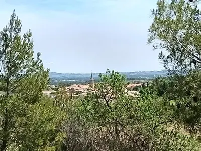 a view of a town from behind some trees at Maison Magnolia in Marcorignan