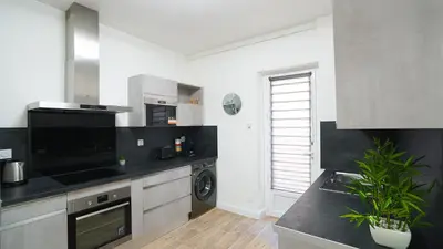a kitchen with a black counter top and a dishwasher at Appartement Les Halles 2, Climatisation, Terrasse, Garage in Narbonne