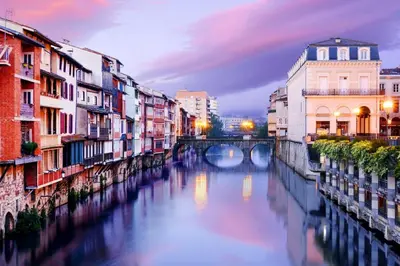 a river in a city with buildings and a bridge at Villa 140 m² hab. avec piscine in Castres