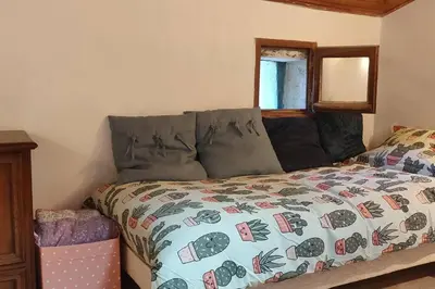 a bedroom with a bed with a comforter and a window at VILLA VILATA A PADERN DANS LES CORBIÈRES SAUVAGES in Padern
