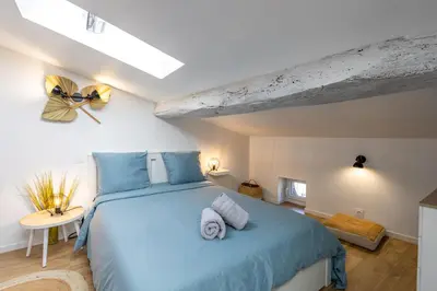 a bedroom with a blue bed with towels on it at L'alouette - Studio Duplex Confort en Hypercentre in Castres