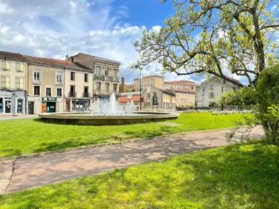 a fountain in the middle of a park with buildings at L'alouette - Studio Duplex Confort en Hypercentre in Castres