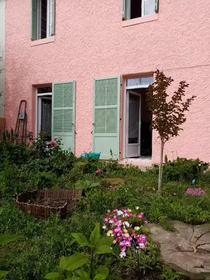 a pink house with green shutters and flowers at Les Toiles du Figuier in Espéraza
