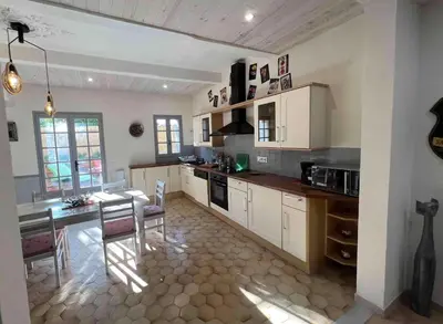 a kitchen with white cabinets and a table with chairs at Superbe Villa avec piscine, 4 chambres à Vinassan in Vinassan