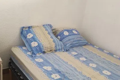 a bed with a blue comforter and pillows at Petit appart sympa clim piscine balcon in Gruissan