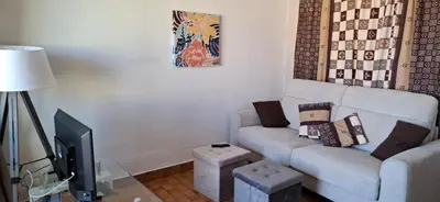 a living room with a couch and a tv at Petit appart sympa clim piscine balcon in Gruissan