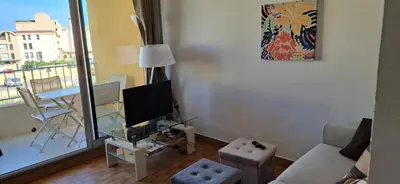 a living room with a couch and a tv and a table at Petit appart sympa clim piscine balcon in Gruissan