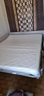 a bed sitting on the floor in a room at Petit appart sympa clim piscine balcon in Gruissan