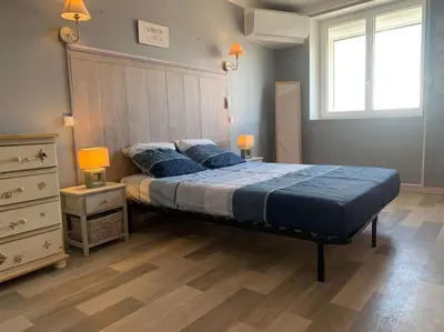a bedroom with a bed with blue sheets and two lamps at Le colibri in Lapalme