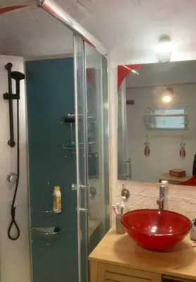 a bathroom with a red sink and a glass shower at Le colibri in Lapalme