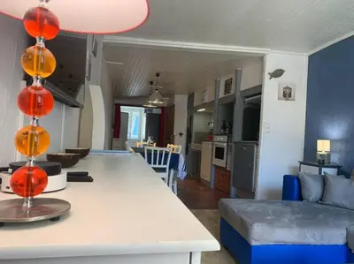a kitchen and living room with a table and a couch at Le colibri in Lapalme