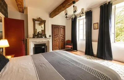 a bedroom with a large bed and a fireplace at Domaine La Belle Histoire - Gîte côté Parc in Besset