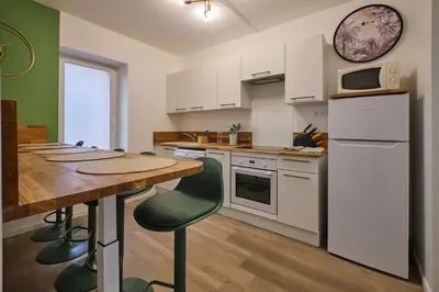 a kitchen with white cabinets and a wooden table at Magnifique T3 centre ville avec WIFI RDC in Limoux
