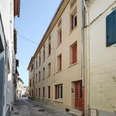 an alley in an old building with red doors at Magnifique T3 centre ville avec WIFI RDC in Limoux