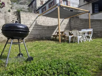 a grill in a yard with chairs and a table at Grand gîte au cœur des Pyrénées - Ariège Mijanes in Mijanès