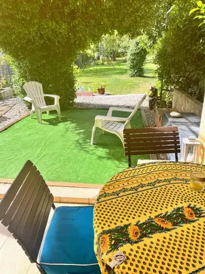 a patio with two chairs and a table and grass at chambre et salle de bain privé s'ouvrant sur terrasse, jardin et cuisine d'été in Quillan